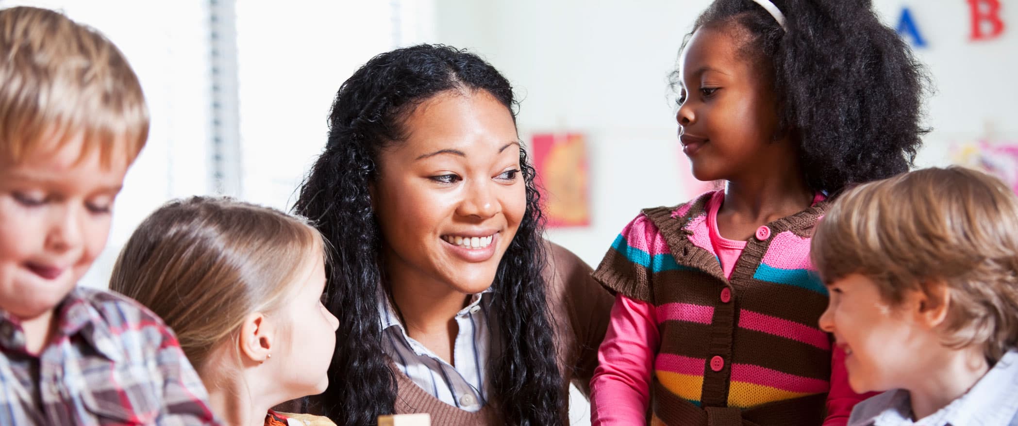 A Morgan’s Early Learning Centers teacher smiling with four children gathered around her